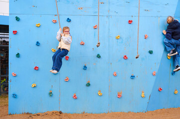 Fototapeta premium Children climbing on climbing wall in playground