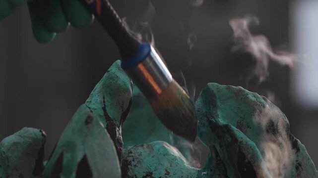 Process of patination on metal surface using brush to apply protective layer in art studio