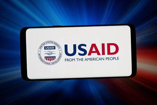 Stuttgart, Germany - 06-11-2026: In this photo illustration, the logo of Agency for International Development (USAID) is displayed on a smartphone in front of abstract background on computer screen.