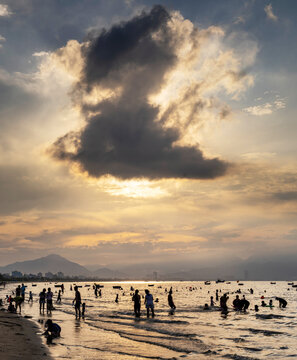 Silhouettes of bathers,swimming after sunset,in the warm sea at Da Nang Beach,Vietnam..