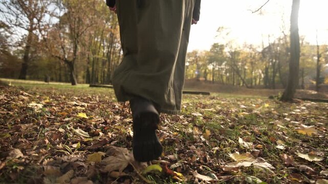 Elegant Legs In Leather Boots Crunching On Autumn Leaves In The Park