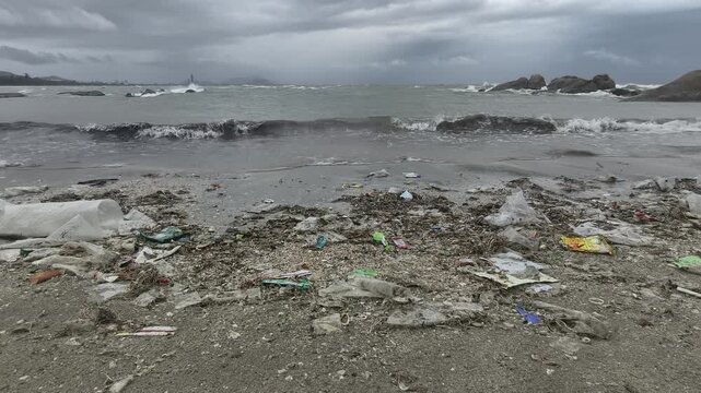 Sea waves washing plastic garbage and debris ashore on the beach during monsoon season