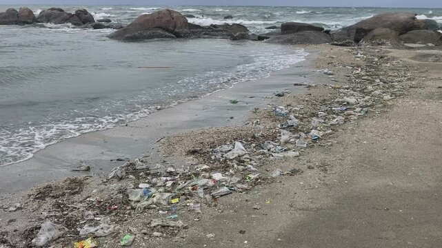 Sea waves washing plastic garbage and debris ashore on the beach during monsoon season