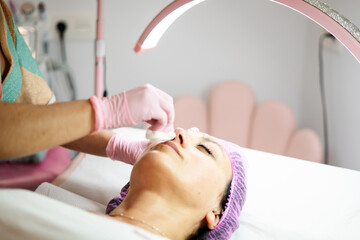 Naklejka premium Woman getting facial skincare treatment at beauty salon