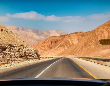 driving a car on the mountain road in the desert view of sandstone mountains through the windscreen the road from arad to the dead sea israel