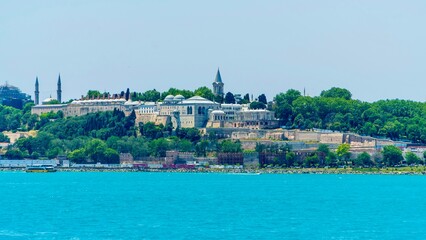 Istanbul, Turkey - June 14, 2026: View of Topkapi Palace from the Bosphorus in Istanbul, Turkey, showing the historic Ottoman palace complex, waterfront location, palace walls, domes, and trees © batkanov