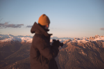 Photographer admiring snow-covered mountain ranges during sunset in the Dolomites. Atmospheric alpine landscape with warm evening light and distant peaks © Ivan Kmit
