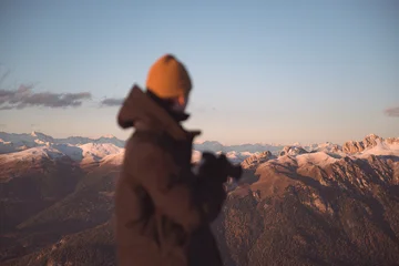 Photographer admiring snow-covered mountain ranges during sunset in the Dolomites. Atmospheric alpine landscape with warm evening light and distant peaks © Ivan Kmit