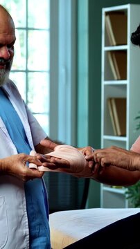 Indian physiotherapist treating wrist pain by applying support band as experienced male therapist helps patient relieve injury inside modern Indian clinic OPD healthcare treatment visit
