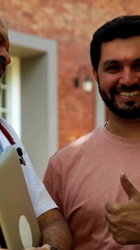 Smiling Indian doctor patient outdoors showing ok sign to camera while standing in natural greenery as senior male physician and young patient celebrate positive healthcare outcome together