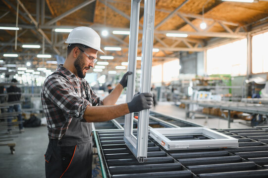 Factory worker assembling modern pvc window frame in manufacturing workshop