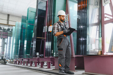 Fototapeta premium Factory worker inspecting glass panels in manufacturing plant