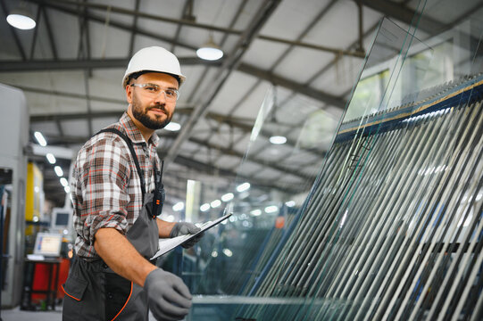 Worker checking glass panels in window factory