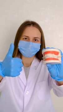 A dentist shows a model of a jaw. Selective focus.