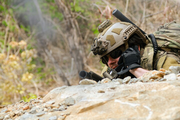 Fototapeta premium The sacrificing soldiers lie prostrate on the ground camouflaged behind rocks preparing fire upon the enemy on the ground in a ready to attack stance. 
