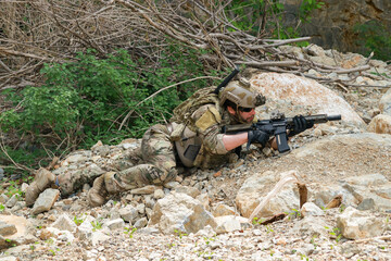 Fototapeta premium The sacrificing soldiers lie prostrate on the ground camouflaged behind rocks preparing fire upon the enemy on the ground in a ready to attack stance. 