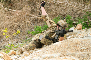 Fototapeta premium The sacrificing soldiers lie prostrate on the ground camouflaged behind rocks preparing fire upon the enemy on the ground in a ready to attack stance. 