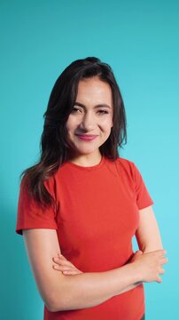 Shy and flirty woman smiling and blushing on blue background