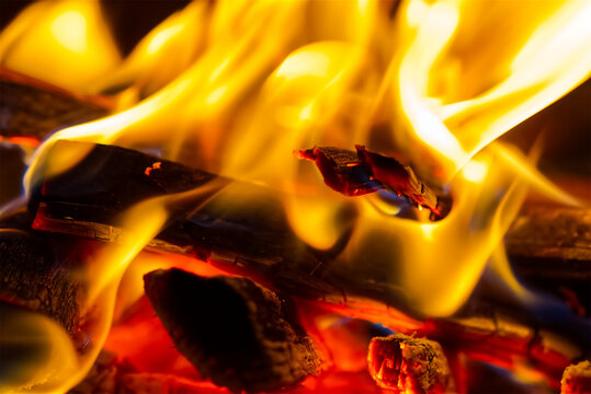 Macro photography of burning wood and glowing embers in a fire, with shallow depth of field