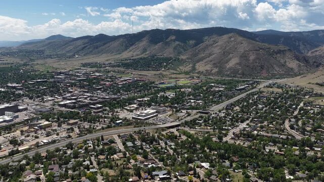 Wide Aerial of residential and commercial development in Golden Colorado showing a mix of suburban neighborhoods major roads and foothills under cloudy skies in summer