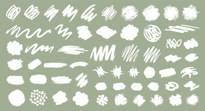 Large collection of diverse white chalk scribbles brush strokes and textures on a solid green background for artistic design elements.