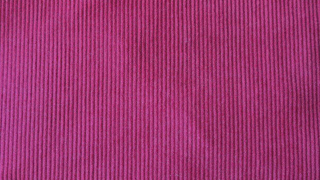 Pink corduroy ribbed fabric texture close up.
