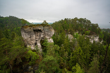 Fototapeta premium Rock city formations in Hruboskalsko, Bohemian Paradise (Cesky raj), Czech Republic, with peaks of giant sandstone rocks and cliffs emerging from light morning mist panoramic view