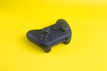 Angled view of blank black gamepad controller mockup on yellow background for gaming design.  © wibiwisnu