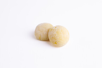 Fototapeta premium Two yellow mochi covered in powder on a white background. Traditional japanese sweet dessert ready for advertising layout. 