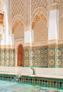 a refreshing water feature in a quiet historic riad courtyard showcasing colorful mosaic zellij tiles in Ben Youssef Madrasa, morocco architecture