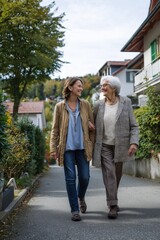 Obraz premium Daughter walking with elderly mother outdoors on quiet street family care concept