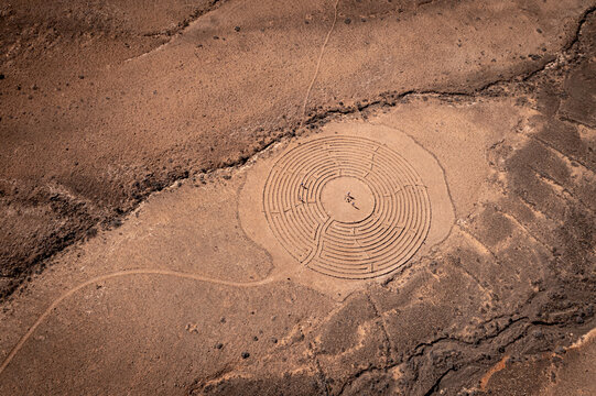 Aerial view of the Wolfs Labyrinth in the arid volcanic landscape with people standing in the center El Cotillo, Canary Islands, Spain.