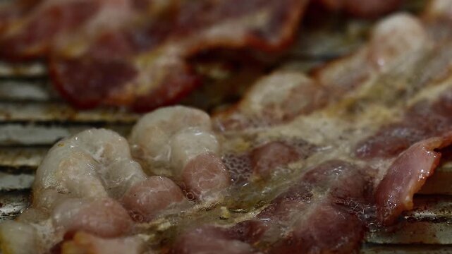 Extreme close-up of bacon frying in pan with bubbling oil, sizzling fat, unhealthy cholesterol food, crispy meat cooking, greasy breakfast, guilty pleasure, delicious but dangerous