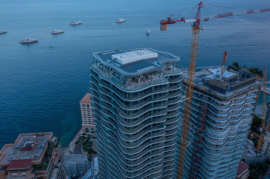 Aerial view of modern skyscrapers under construction with tall cranes overlooking the Mediterranean Sea and yachts at dusk in Monte Carlo, Monaco, Monaco.