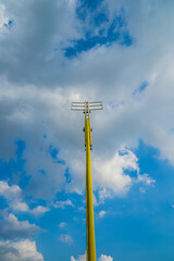 Obraz premium Yellow street light pole against blue sky with white clouds