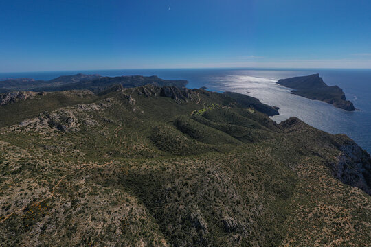 Aerial view of the rugged cliffs of Mirador Josep Sastre overlooking the Mediterranean Sea and Sa Dragonera island under a clear blue sky in Andratx, Balearic Islands, Spain.
