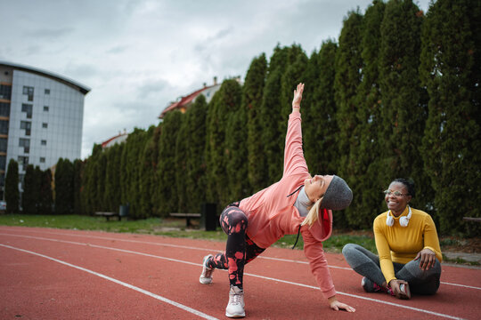 Women friends stretching on running track together