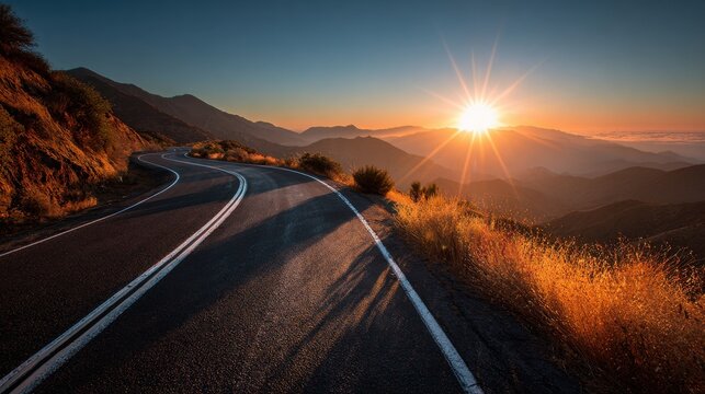 Scenic mountain road at sunrise with sunburst