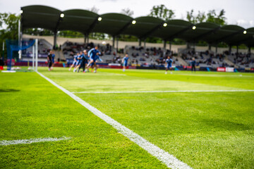 Fototapeta premium Goal line at first plane and blurred soccer players in action during match, real dynamic sports moment captured in stadium with crowd.
