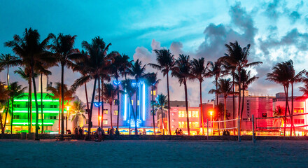Fototapeta premium Miami Beach Ocean Drive hotels and restaurants at sunset. City skyline with palm trees at night. Art deco nightlife on South beach