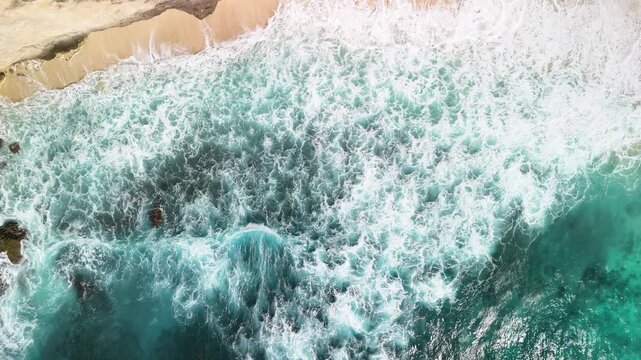 Powerful white surf breaking waves aerial top-down view over turquoise ocean Nusa Penida