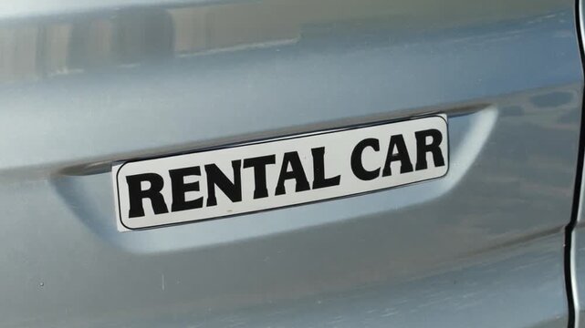 A sticker on a car reads "Rental car".