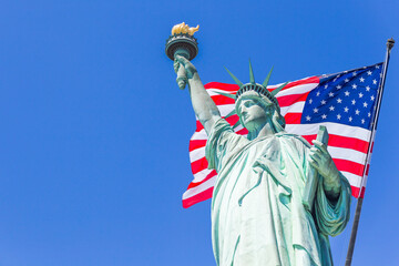 Statue of Liberty with a large american flag and New York skyline in the background © Maria