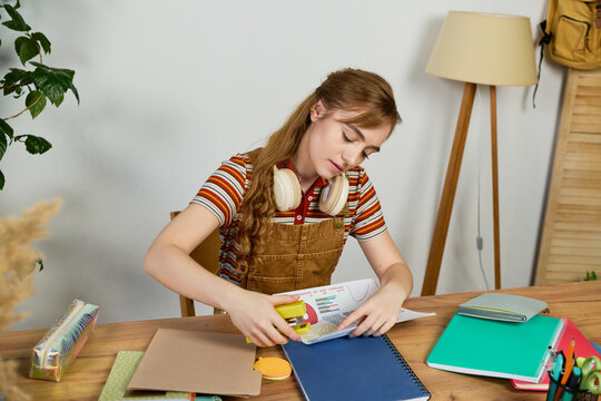 Young student engaged in creative study with notebooks and colorful supplies in a cozy space