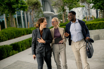 Group of colleagues walking together in a modern outdoor setting during the day © BGStock72