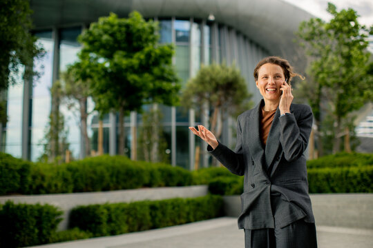 Woman talking on phone outside modern building in daylight