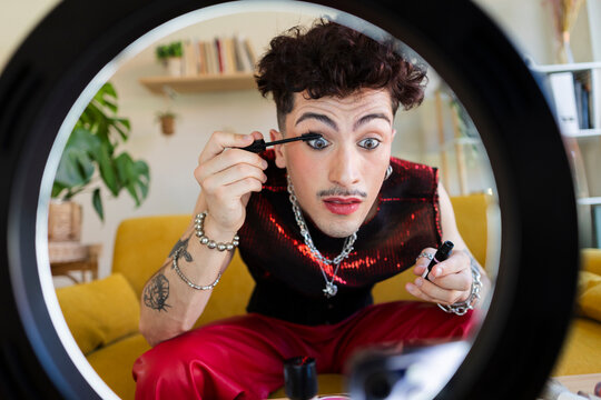 Person applying mascara filming beauty content with ring light