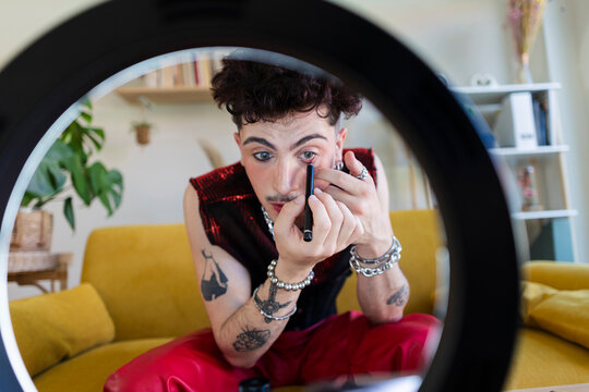 Young person applying eye makeup looking at ring light