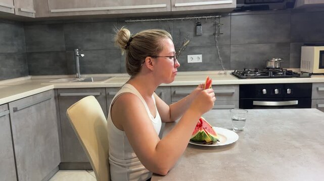 Young woman eating watermelon at modern kitchen island