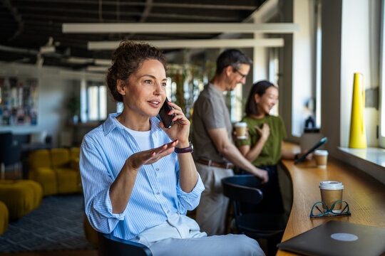 Businesswoman talking on phone smiling in modern office
